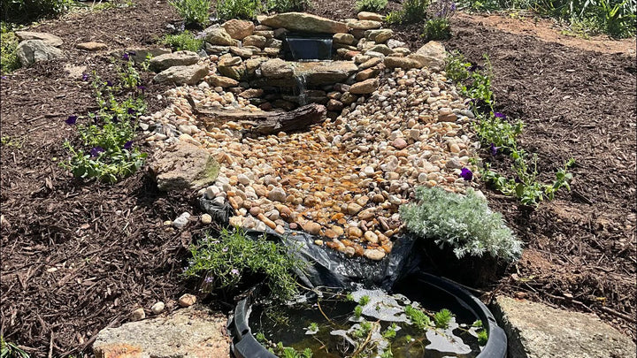DIY pondless waterfall project with rocks, plants, and moving water